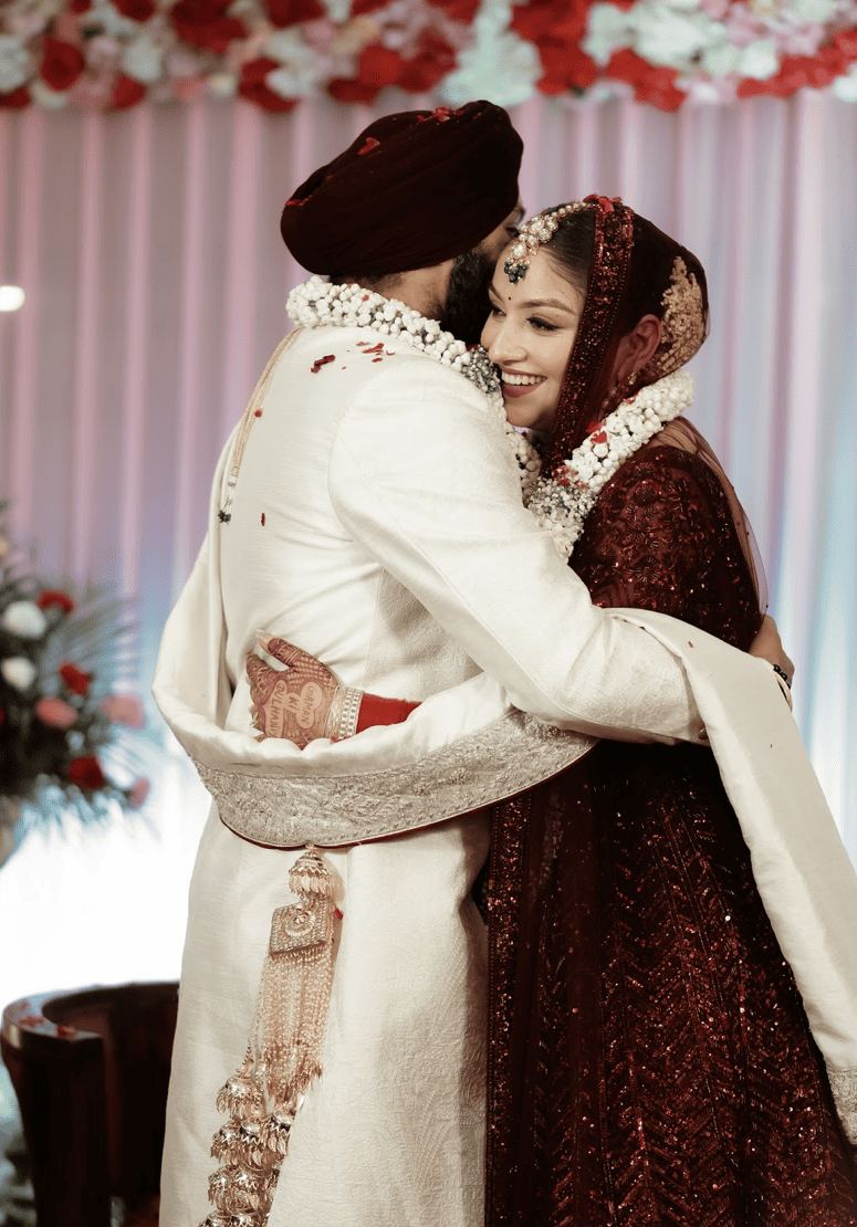 Newlywed couple embrace with floral garlands